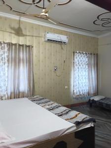 uma cama num quarto com uma ventoinha e janelas em ARVINDAM VILLA HOMESTAY-THE ESSENCE OF RAMA em Ayodhya