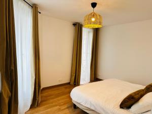 ein Schlafzimmer mit einem Bett und einer Hängeleuchte in der Unterkunft Appartement F2 - Stade de France in Saint-Denis