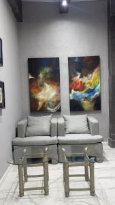 a couch and two tables in a room with paintings at Gran Hotel Cantera La plaza in Nuevo Laredo