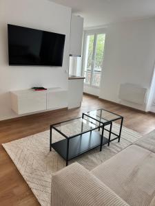 ein Wohnzimmer mit einem Couchtisch aus Glas und einem TV in der Unterkunft Appartement F2 - Stade de France in Saint-Denis