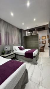 a hotel room with two beds with purple sheets at Gran Hotel Cantera La plaza in Nuevo Laredo