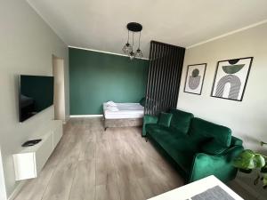 a living room with a green couch and a bed at Apartament Rataje Park Poznań II - Parking - 24h check in in Poznań