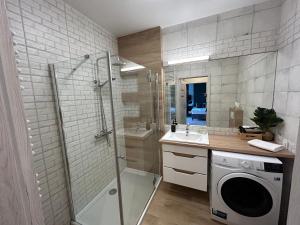 y baño con ducha y lavadora. en Apartament Rataje Park Poznań II - Parking - 24h check in en Poznan