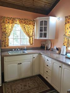 a kitchen with white cabinets and a sink and a window at Dalkeith Greathouse in Mandeville