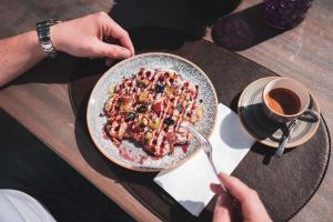 a person holding a plate of food and a cup of coffee at Villa Sonnenhof Boutique-Hotel in Bad Reichenhall