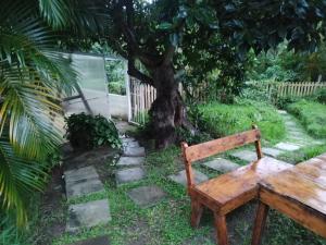 a wooden bench sitting in a yard with a tree at Ficus Cottage - Ramsgate Ramble Rest in Margate