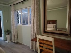 a mirror in a room with a bed and a chair at Ficus Cottage - Ramsgate Ramble Rest in Margate