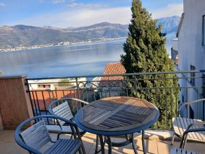 a table and chairs on a balcony with a view of the water at Apartman sa bazenom in Radovići