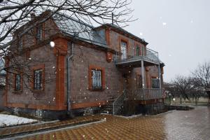 un antiguo edificio de ladrillo con balcón en la nieve en Вила Eco Garden en Gyumri