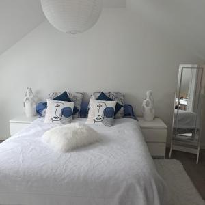 - un lit blanc avec des oreillers bleus et blancs et un miroir dans l'établissement Maison de 2 chambres avec jardin clos et wifi a Saint Cyr la Riviere, 