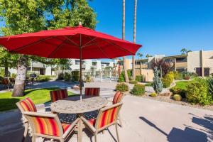a table and two chairs with a red umbrella at Modern Townhouse-Walk 2 OldTown-4 Heated Pools in Scottsdale