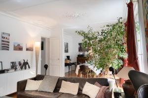 een woonkamer met een bank en een plant bij Luxueux et spacieux 100m², Faidherbe, 11th ard in Parijs