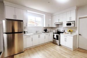 a kitchen with white cabinets and a stainless steel refrigerator at Gorgeous 2 Bedrooms Suite Private entrane with patio-Free Parking in Maple Ridge