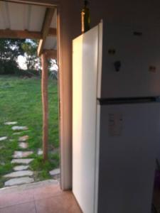 a kitchen with a refrigerator and an open door at habitación en casa de campo in La Paloma