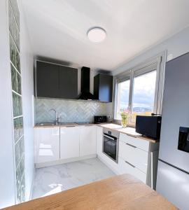 cocina con armarios blancos y ventana grande en 5 minutes metro free parking 2 bedrooms 4-6P Near Paris, en Malakoff