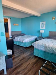 Habitación con 2 camas, paredes azules y suelo de madera. en Lake Point Motel en Marblehead