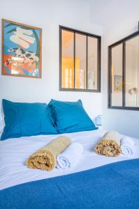 a large white bed with blue pillows on it at Le Petit Jaune : Centre ville T2 avec balcon in Marseille