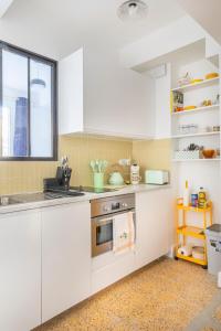 a kitchen with white cabinets and a window at Le Petit Jaune : Centre ville T2 avec balcon in Marseille