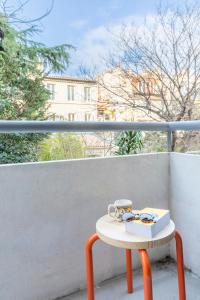 a table with a book and a cup on a balcony at Le Petit Jaune : Centre ville T2 avec balcon in Marseille