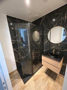 ein schwarzes Bad mit einem Waschbecken und einem Spiegel in der Unterkunft Appartement tout confort in Harfleur