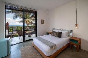 a bedroom with a bed with a view of the ocean at Tropicalito Villa on the Beach in Tulum