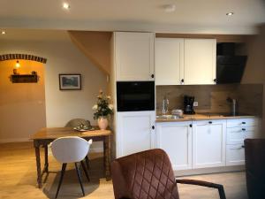 a kitchen with white cabinets and a wooden table at Hollema Logies - De Pastorie in Earnewâld