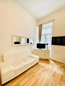 ein Wohnzimmer mit einem weißen Sofa und einem TV in der Unterkunft Cozy Studio LG in Wien
