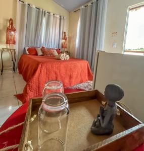 a room with a bed and a table with a glass at Villa Madeira in Alto Paraíso de Goiás