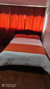 1 dormitorio con 1 cama con cortina naranja en Gran Hostal Casa Luz, en Quito