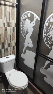 uma casa de banho com WC e uma parede com um desenho de uma mulher com em Gran Hostal Casa Luz em Quito