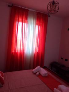 a bedroom with a red curtain and a bed at Hausen Margaret's in Kuçovë