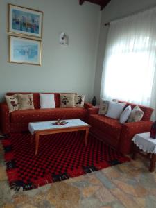 a living room with a red couch and a coffee table at Hausen Margaret's in Kuçovë