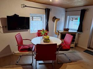 ein Esszimmer mit einem Tisch und roten Stühlen in der Unterkunft Ferienwohnungen Treseburg "Zur Bodehexe" in Thale