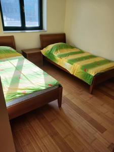 two beds in a room with wooden floors at Apartman Olja in Radovići