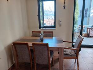 a dining room table with chairs and a large window at Apartman Olja in Radovići