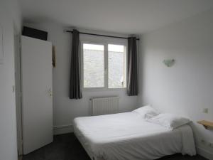 a bedroom with a white bed and a window at hôtel de la grange in Cossé-le-Vivien