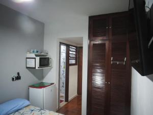 a small room with a bed and a microwave at Suites 500m Praia da Enseada in Guarujá