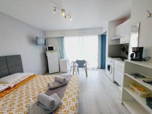 a bedroom with a bed and a kitchen with a window at Studio Moderne - Plage du Grazel in Gruissan