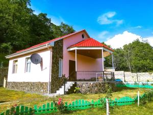 une petite maison rose avec un toit rouge dans l'établissement Guliyev Home, à Qax