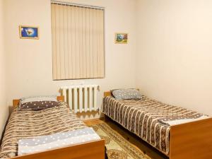 a bedroom with two beds and a window and a radiator at Guliyev Home in Qax