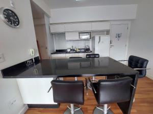 a kitchen with a black counter top and chairs at Book Santos - Unlimited 1709 - Apartamento Vista Mar in Santos