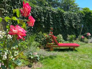 a red bench in a garden with flowers at Rezydencja Grawert Boutique & Spa in Lądek-Zdrój