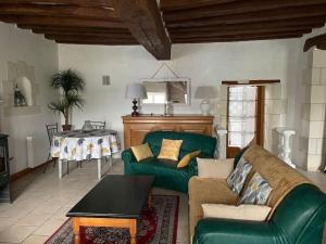 uma sala de estar com um sofá verde e uma mesa em Gîte La Carillonnerie em Bossay-sur-Claise