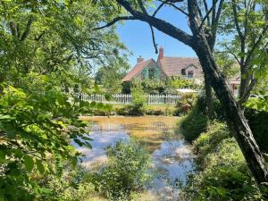 a house with a pond in front of a fence at Gîte Nature la Carillonnerie in Bossay-sur-Claise +21 photos