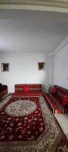 a living room with a red couch and a rug at Villa Neji, Havre de pierre à 10 min de la plage. in Korba