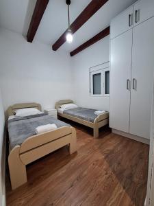 two beds in a room with wooden floors and white walls at Holiday home Bobija Skadar lake in Karuč