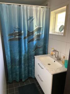 ein Badezimmer mit einem Waschbecken und einem Duschvorhang mit Delfinen in der Unterkunft Litet modernt fristående hus i Skärgården på Värmdö, Stockholm in Värmdö