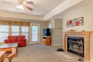a living room with a fireplace and a red couch at Branson Condo at Stonebridge Golf Resort with Pool and Wi-Fi near Silver Dollar City and 76 in Reeds Spring