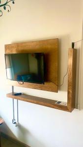 a tv on a wall with a wooden shelf at Casa Edka in Ensenada