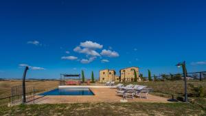 a group of chairs sitting around a pool in front of a building at Podere Fossaccio Casa Girasole in Asciano